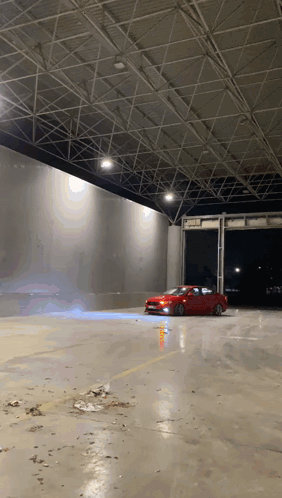 A Red Car Is Driving Down A Concrete Road GIF