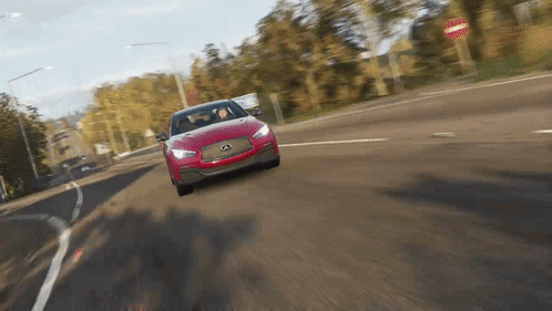 A Red Car Is Driving Down A Road With A No Entry Sign In The Background GIF