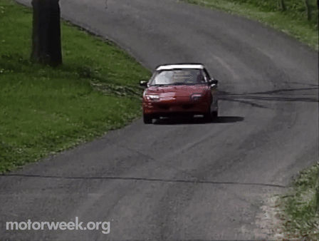 A Red Car Is Driving Down A Road With Motorweek.org Written On The Bottom Right GIF