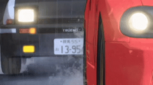 A Red Car Is Driving Next To A Black Car On A Road . GIF
