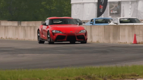 A Red Car Is Driving On A Track With A Sign That Says Greddy GIF
