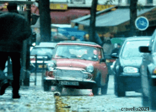 A Red Car With A License Plate That Starts With The Letter C Is Driving Down A Busy Street GIF