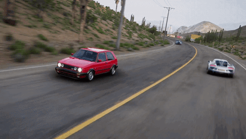 A Red Car With The Word Volkswagon On The Side Is Driving Down A Road GIF
