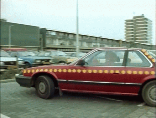 A Red Car With Yellow Circles On It Is Parked In A Parking Lot GIF