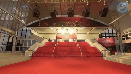 A Red Carpet Leading Up To A Stage With A Sign That Says " Cannes " GIF