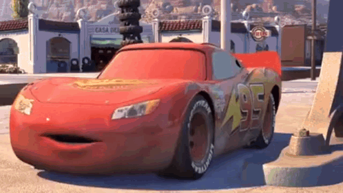 A Red Cartoon Car With A Big Mouth Is Parked On The Side Of The Road In Front Of A Building . GIF