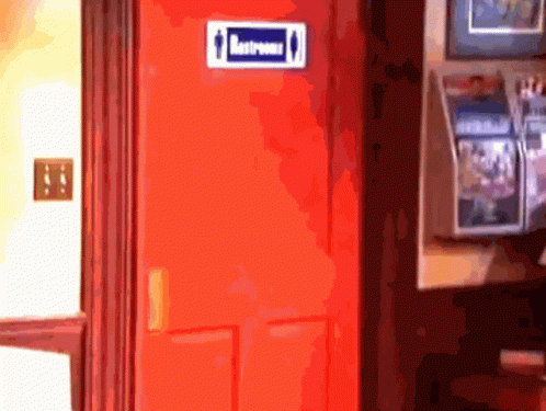 A Red Door With A Blue Sign On It That Says Restrooms GIF