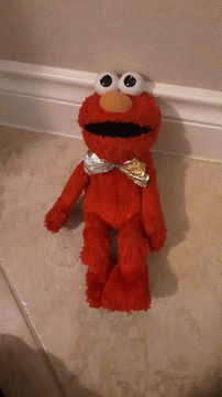 A Red Elmo Stuffed Animal Is Standing On A Tiled Floor GIF