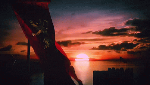 A Red Flag With A Lion On It Is Flying In Front Of A Sunset Over A Body Of Water GIF