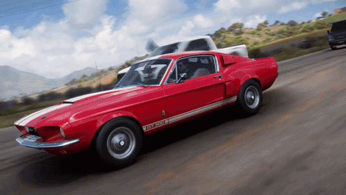 a red ford mustang gt500 is driving down the road