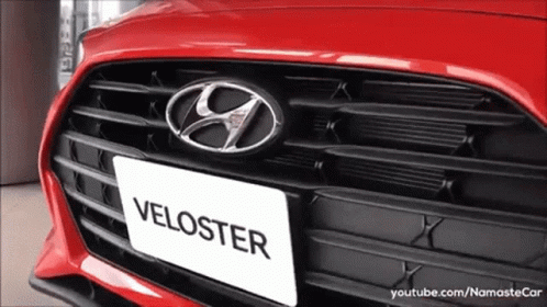 A Red Hyundai Veloster Is Displayed In A Showroom GIF