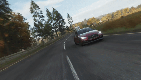 A Red Infiniti Car Is Driving Down A Road With Trees In The Background GIF