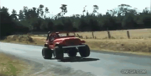A Red Jeep Is Driving Down A Road Next To A Field GIF