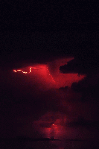 A Red Lightning Bolt Strikes The Ground In The Night Sky GIF