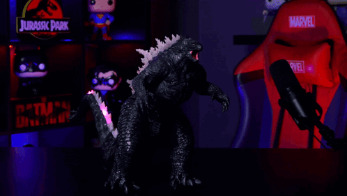 A Red Marvel Chair Sits In Front Of A Glowing Godzilla Figure GIF