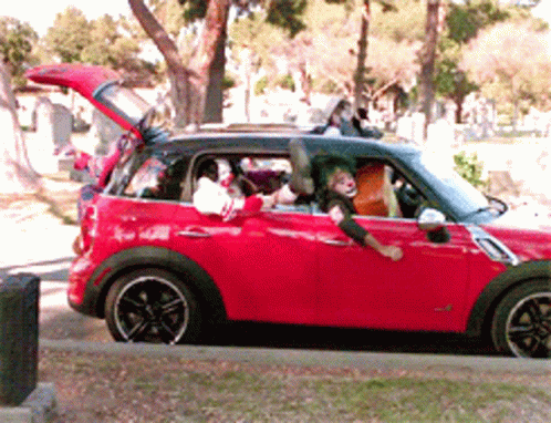 A Red Mini Cooper With A Clown In The Driver 'S Seat GIF