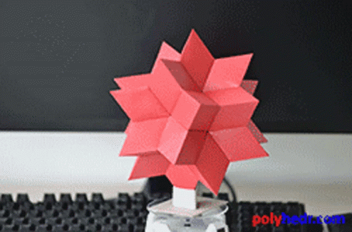 A Red Origami Object Is Sitting On A Table Next To A Keyboard GIF