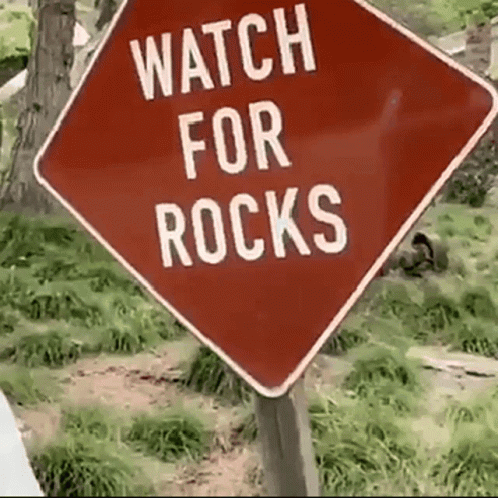 A Red Sign Says Watch For Rocks On It GIF