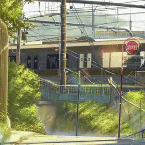 A Red Sign That Says Stop On It In Front Of A Train Station GIF