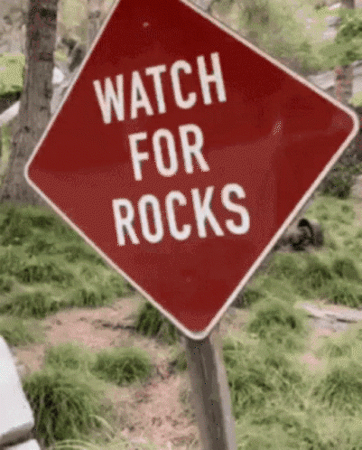 A Red Sign That Says Watch For Rocks GIF
