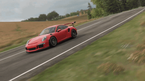 A Red Sports Car Is Driving Down A Road With Grass On The Side GIF