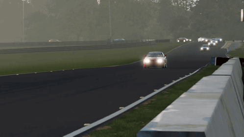 A Red Sports Car Is Driving Down A Track With Its Headlights On GIF