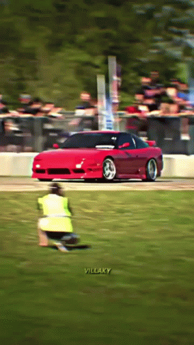 A Red Sports Car Is Driving Down A Track With The Words Villaky On The Bottom Right GIF