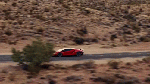 A Red Sports Car Is Driving On A Desert Road GIF