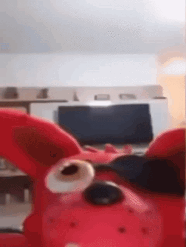 A Red Stuffed Animal Wearing Sunglasses Is Sitting In Front Of A Laptop Computer . GIF