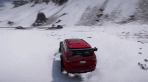 A Red Suv Is Driving Through The Snow On A Mountain GIF