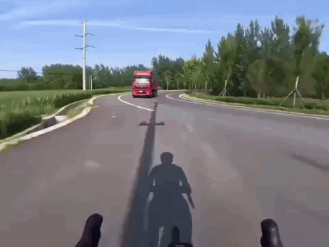 A Red Truck Driving Down A Road With A Shadow Of A Person On The Ground GIF