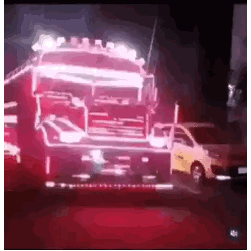 a red truck is driving down a street with a white van in the background .