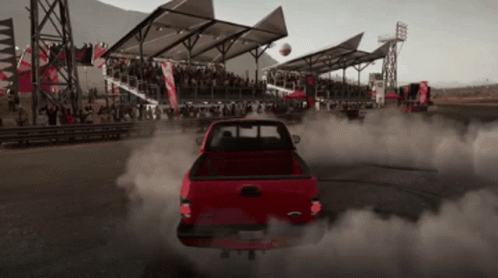 A Red Truck Is Driving Down A Track With Smoke Coming Out Of The Back GIF