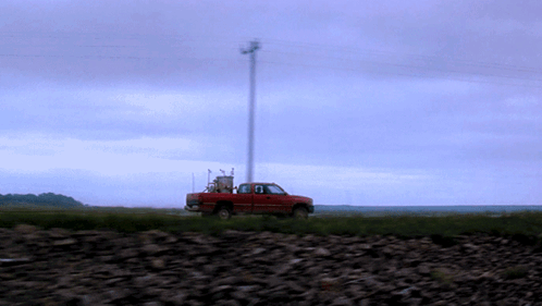 A Red Truck Is Parked In The Middle Of A Rocky Field GIF