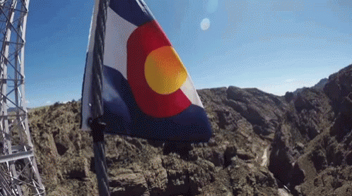 A Red White And Blue Flag With A Yellow Center Is Flying In The Wind GIF