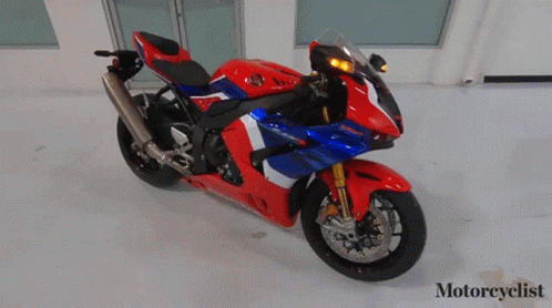 A Red White And Blue Honda Motorcycle Is Parked In A Room GIF