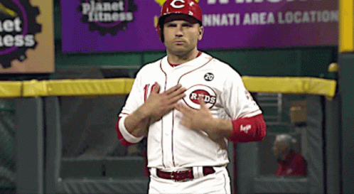 A Reds Baseball Player Stands In Front Of A Planet Fitness Ad GIF