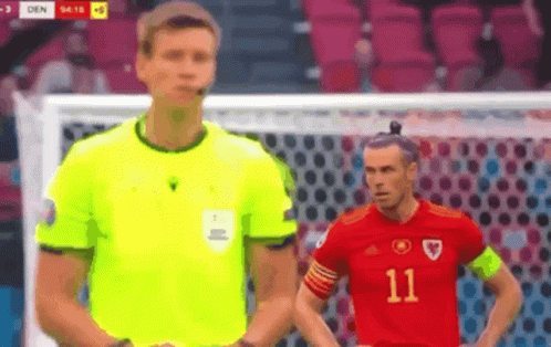 A Referee And A Soccer Player Are Standing Next To Each Other . GIF