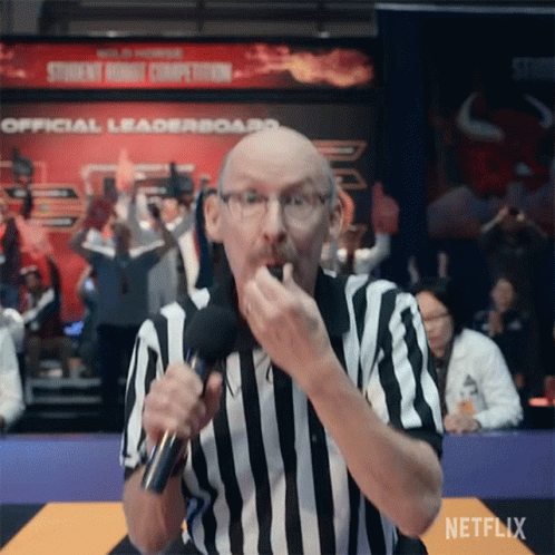 A Referee In A Striped Shirt Is Holding A Microphone And Eating A Snack . GIF