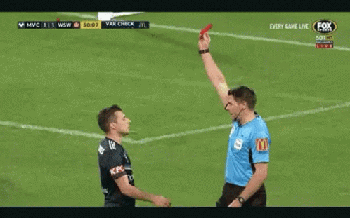 A Referee Is Giving A Red Card To A Player On A Soccer Field . GIF