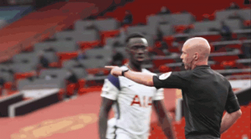A Referee Is Pointing At A Soccer Player Who Is Wearing A Tottenham Shirt GIF
