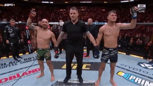 A Referee Is Standing Between Two Men In A Boxing Ring . GIF