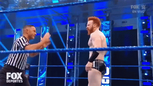 A Referee Is Standing In A Wrestling Ring Talking To A Wrestler During A Fox Deportes Show GIF