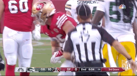 a referee is standing in front of a football player during a game .
