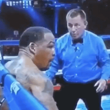 A Referee Is Standing Next To A Boxer In A Boxing Ring . GIF