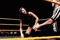 A Referee Is Standing Next To A Woman In A Wrestling Ring Giving The Peace Sign . GIF