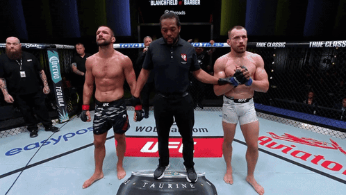 A Referee Stands Between Two Fighters In A Boxing Ring GIF