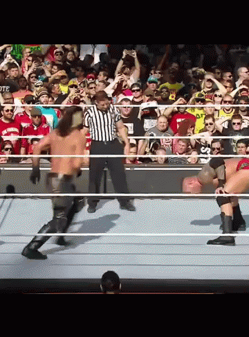 A Referee Stands In The Middle Of A Wrestling Match Between Two Men GIF