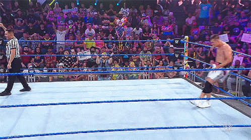 A Referee Stands In The Middle Of A Wrestling Ring Watching A Wrestler GIF