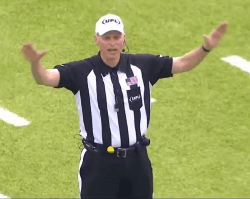 a referee wearing a striped shirt and a white hat with the word ufl on it